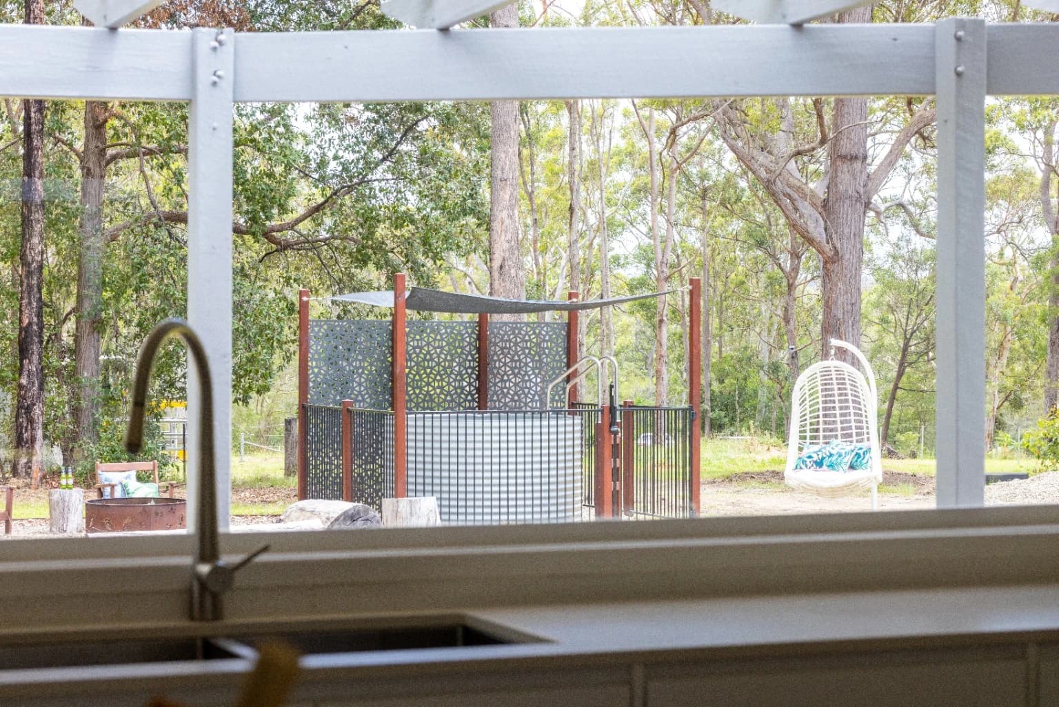 Supplied photograph of an above-ground steel pool in a eucalypt garden, viewed through a kitchen window